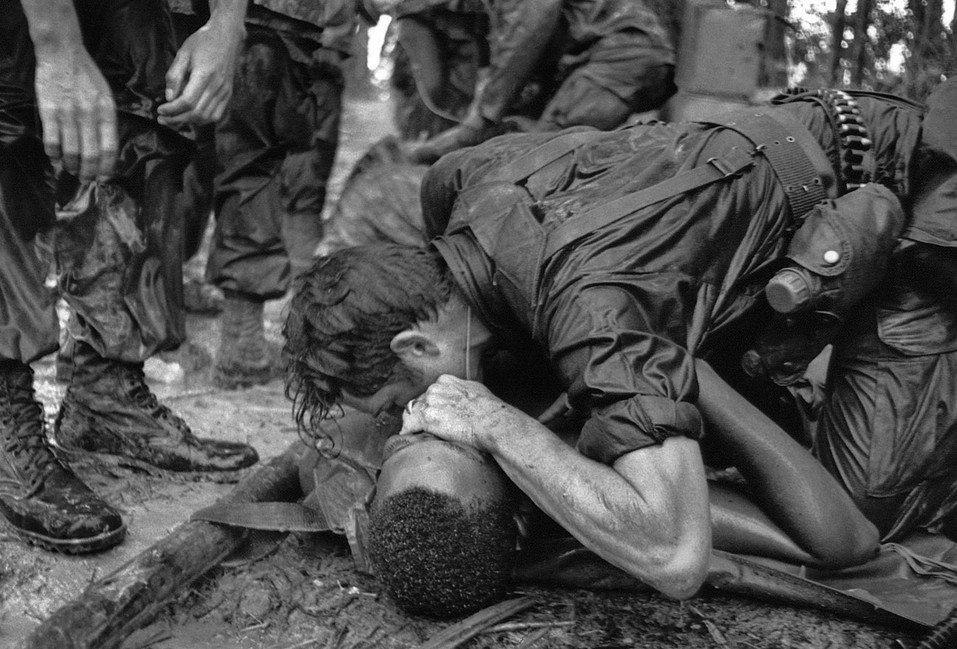 Image [A medic of the 101st Airborne Division attempts to save the life of a fellow medic wounded during the assault against the North Vietnamese at Hamburger Hill. May 19, 1969. The wounded medic later died.][Photo: Hugh Van Es / AP]