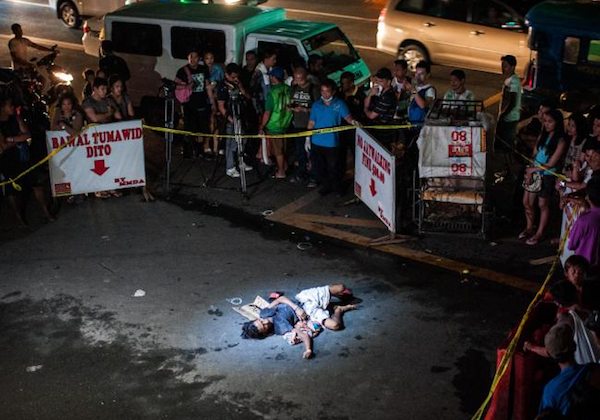 Image An executed alleged drug dealer is surrounded by Duterte supporters bearing anti-drug placards. (Dondi Tawatao)