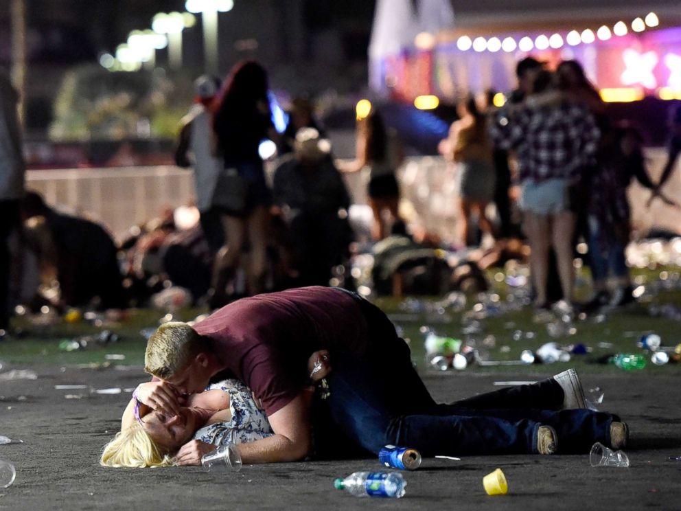 Image A man lays on top of a woman as others flee Las Vegas shooting (ABC News