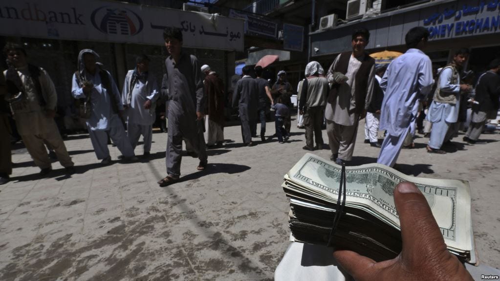 Image A money changer holds a stack of U.S. dollars at Kabul's largest money market April 23, 2014. (Reuters)]