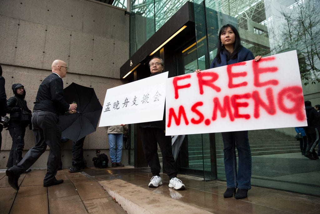 Image Robert Long (L) and Ada Yu hold signs in favor of Huawei Technologies Chief Financial Officer Meng Wanzhou outside her bail hearing at British Columbia Superior Courts following her December 1 arrest in Canada for extradition to the US, December 11, 2018. (Photo by Jason Redmond / AFP) 