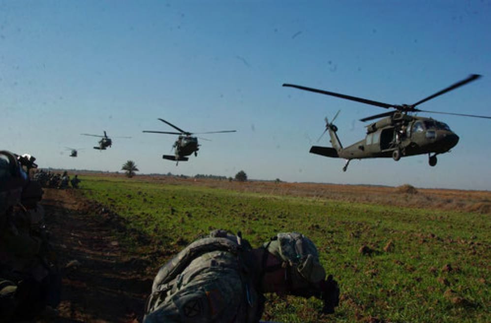 Image [American and Iraqi Soldiers wait as U.S. Army UH-60 Black Hawk helicopters approach their landing zone near Mahmudiyah][Source: DoD photo by United States Forces Iraq (Released)]