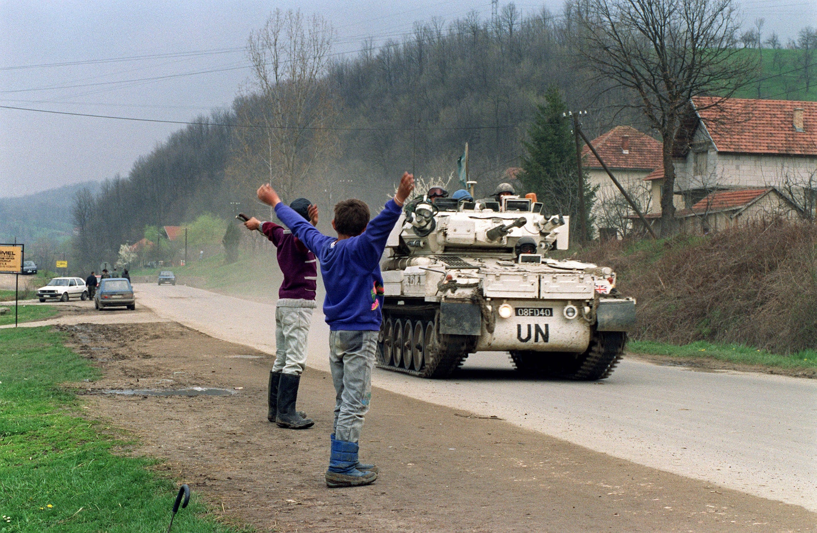 Image Two Bosnian boys salute a U.N. convoy departing for the Muslim enclave of Srebrenica, where some 30000 refugees awaited evacuation, April 17, 1993. (Pascal Guyout)